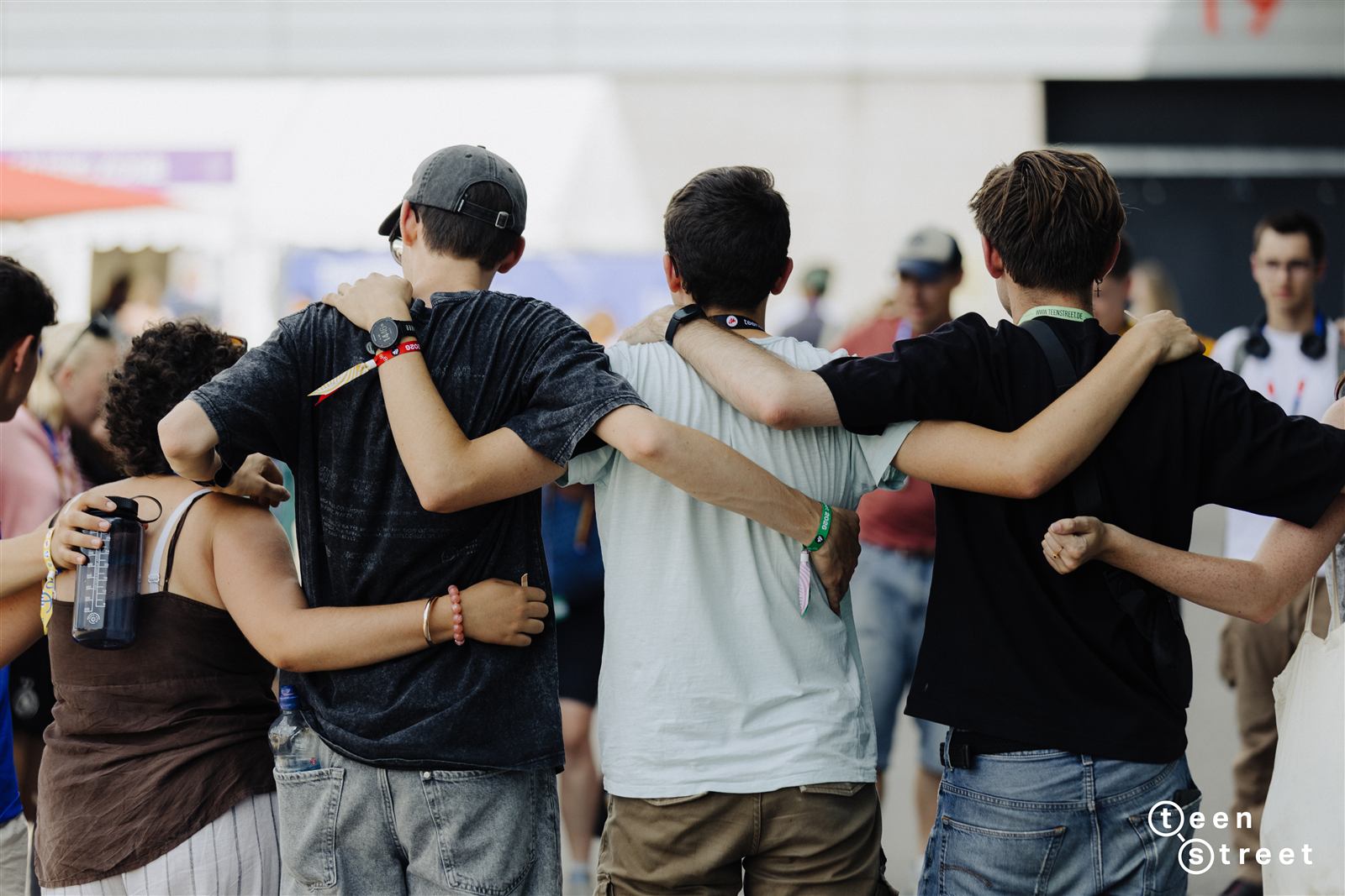 Grupo de adolescentes com os braços nos ombros uns dos outros, de costas para a câmara