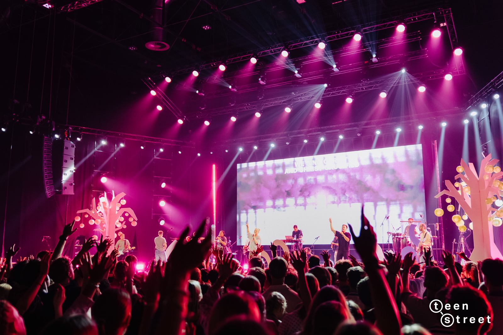 Concerto de louvor no TeenStreet Europa, luzes cor-de-rosa e multidão com as mãos no ar